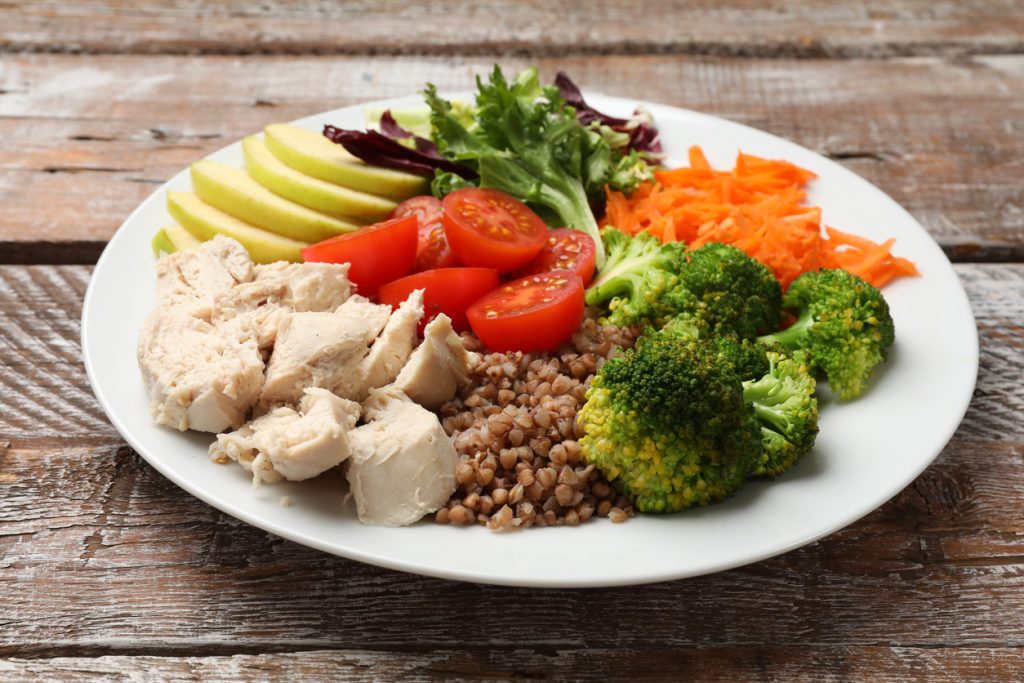 Balanced holiday meal plate with lean chicken, grains, and vegetables showing holiday wellness tips.