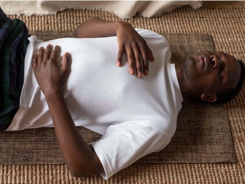 A man holding his hands on his belly while practicing deep breathing exercises to support his parasympathetic nervous system.