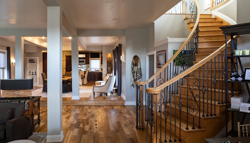 Elegant interior of The Cochrane House featuring a curved staircase, hardwood floors, and curated Black art.