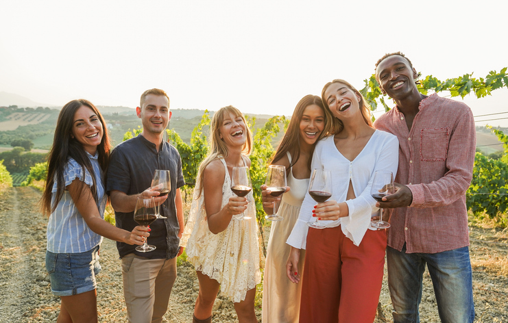Friends celebrating with glasses of wine in a vineyard, capturing the essence of intimate luxury wine experiences and meaningful cultural connections.