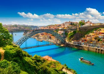 Colorful view of Porto, Portugal with the Dom Luís I Bridge crossing the Douro River on a bright summer day.