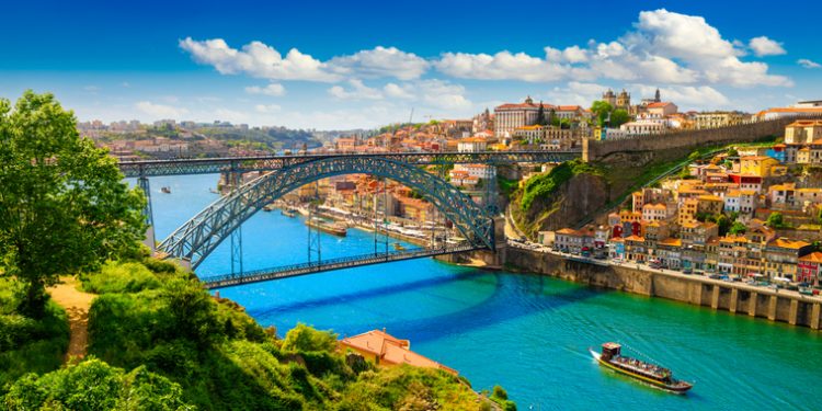 Colorful view of Porto, Portugal with the Dom Luís I Bridge crossing the Douro River on a bright summer day.