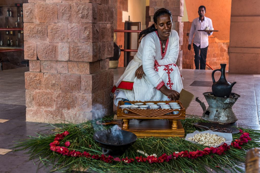 Young woman in traditional dress preparing a coffee ceremony in Lalibela, Ethiopia.
