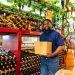 A smiling man standing inside a wine cellar surrounded by bottles and barrels, representing the growth and success of Black-owned wineries.