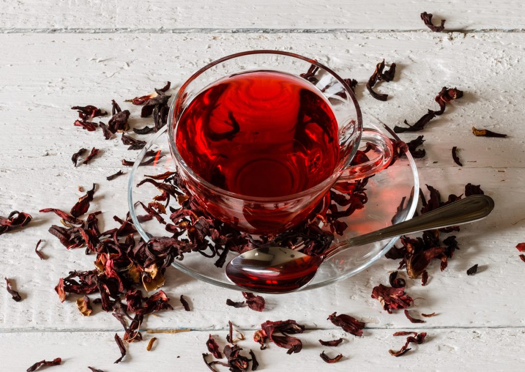 Cup of Karkadeh red tea with dried hibiscus flowers, a traditional Afro-diaspora drink with origins in North Africa and the Caribbean.